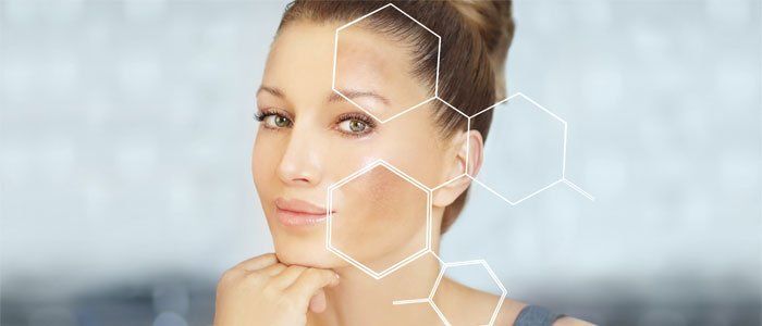 Woman with uneven skin tone, with abstract white molecules overlaying her face. She is smiling.