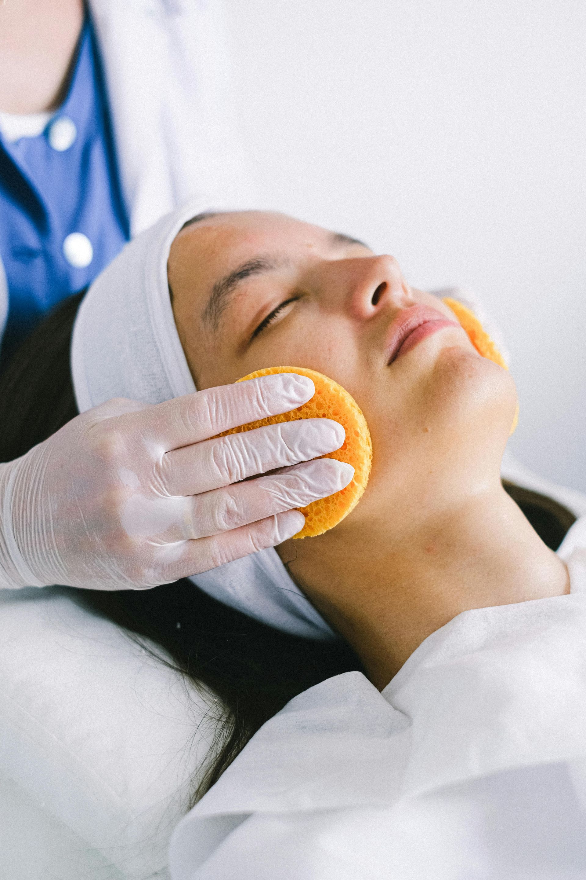 Man receiving laser skin treatment with protective eyewear, performed by gloved hand with laser device.