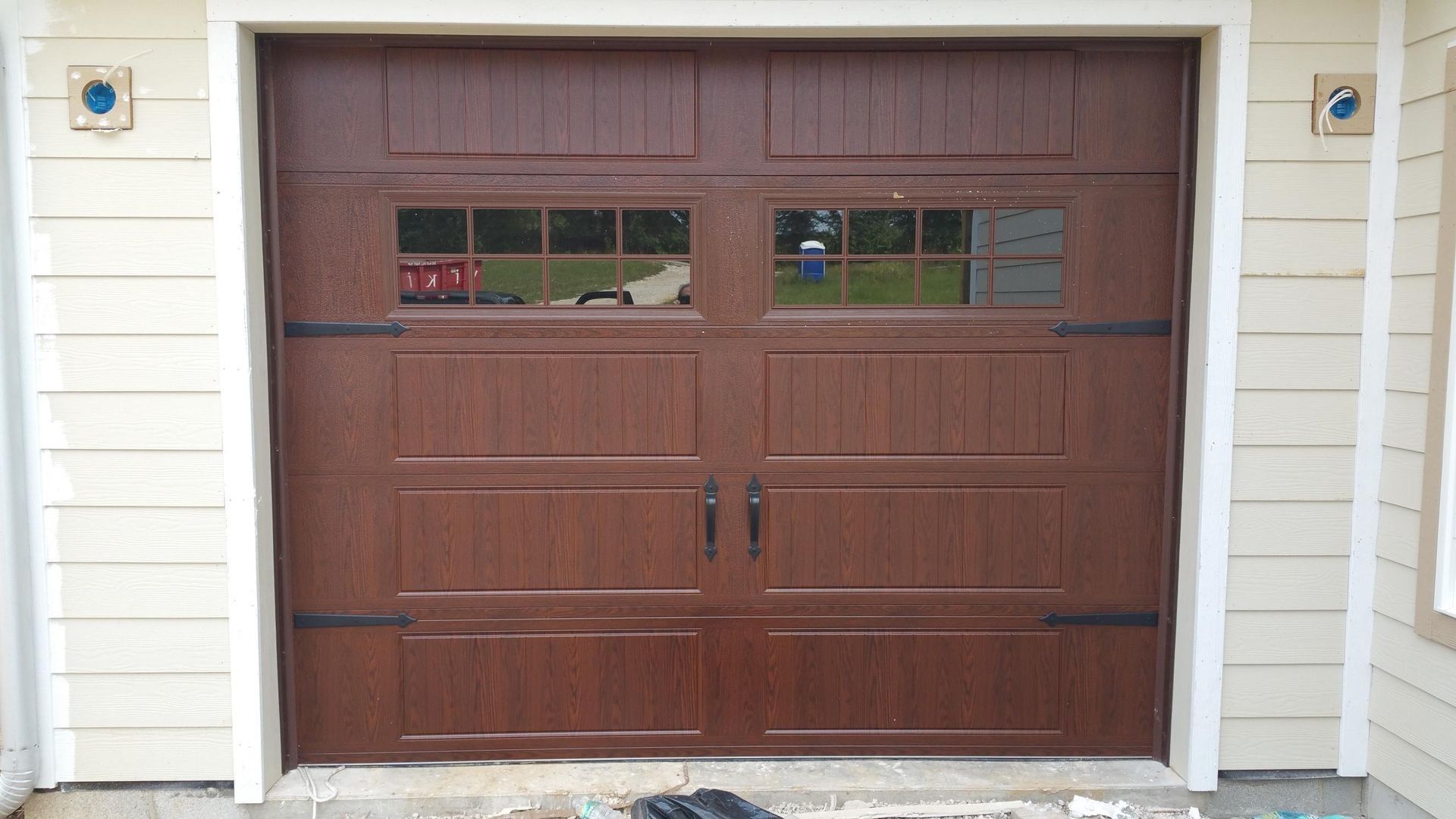 Brown double garage door with small windows on a light exterior wall