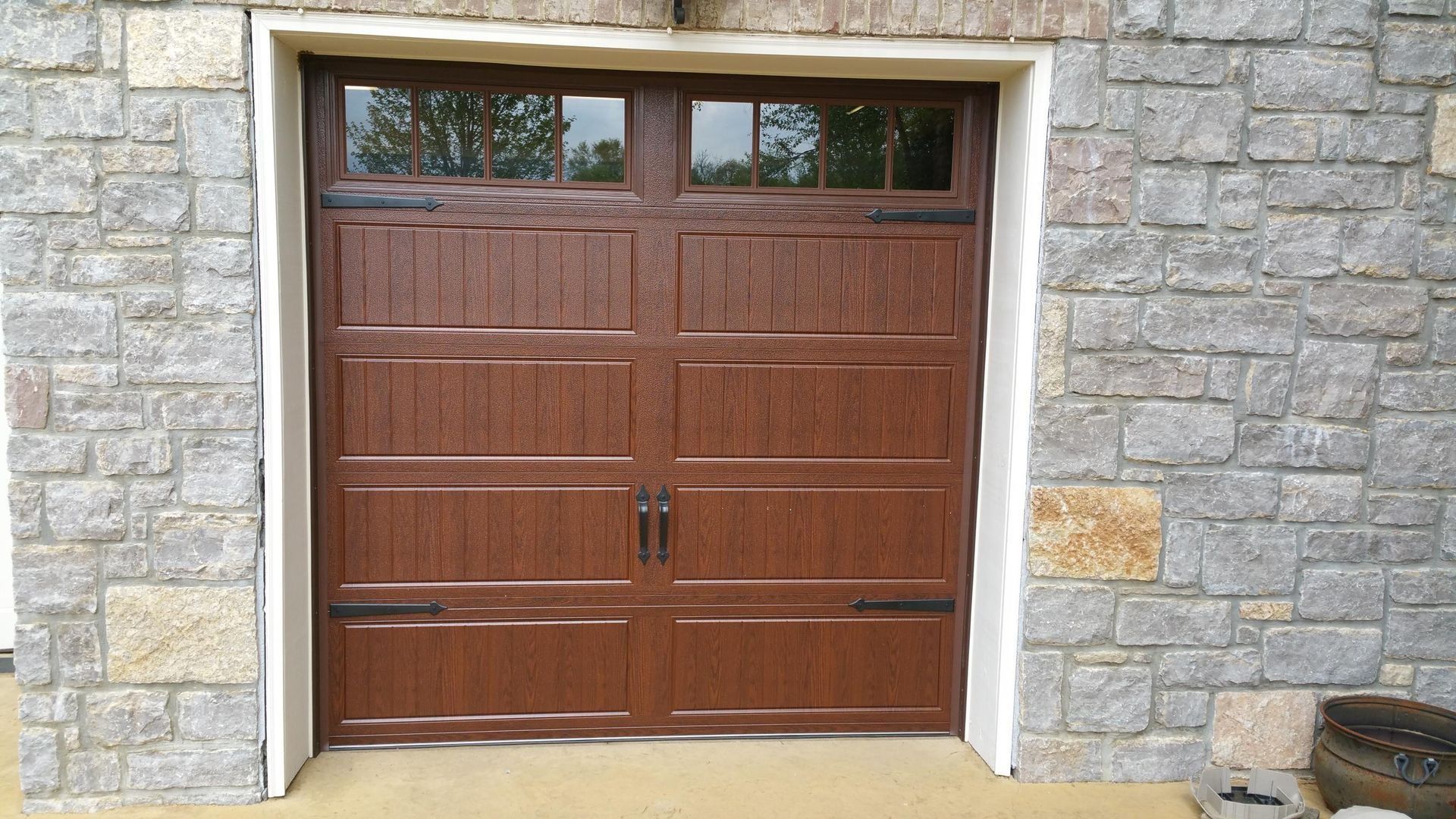 Wooden double garage door set in a stone wall with small upper windows