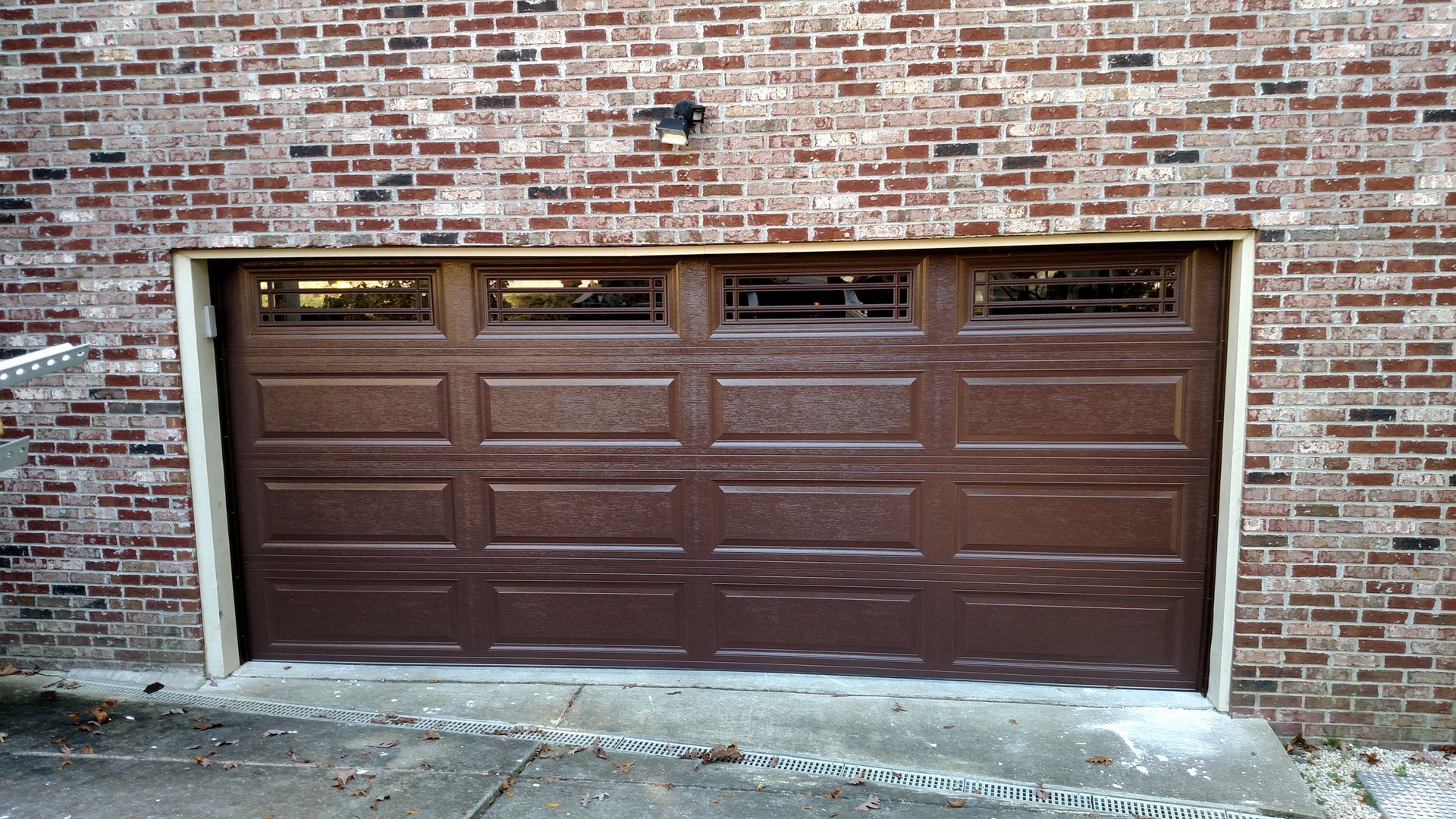 Brown garage door set in a brick wall with three small windows at the top