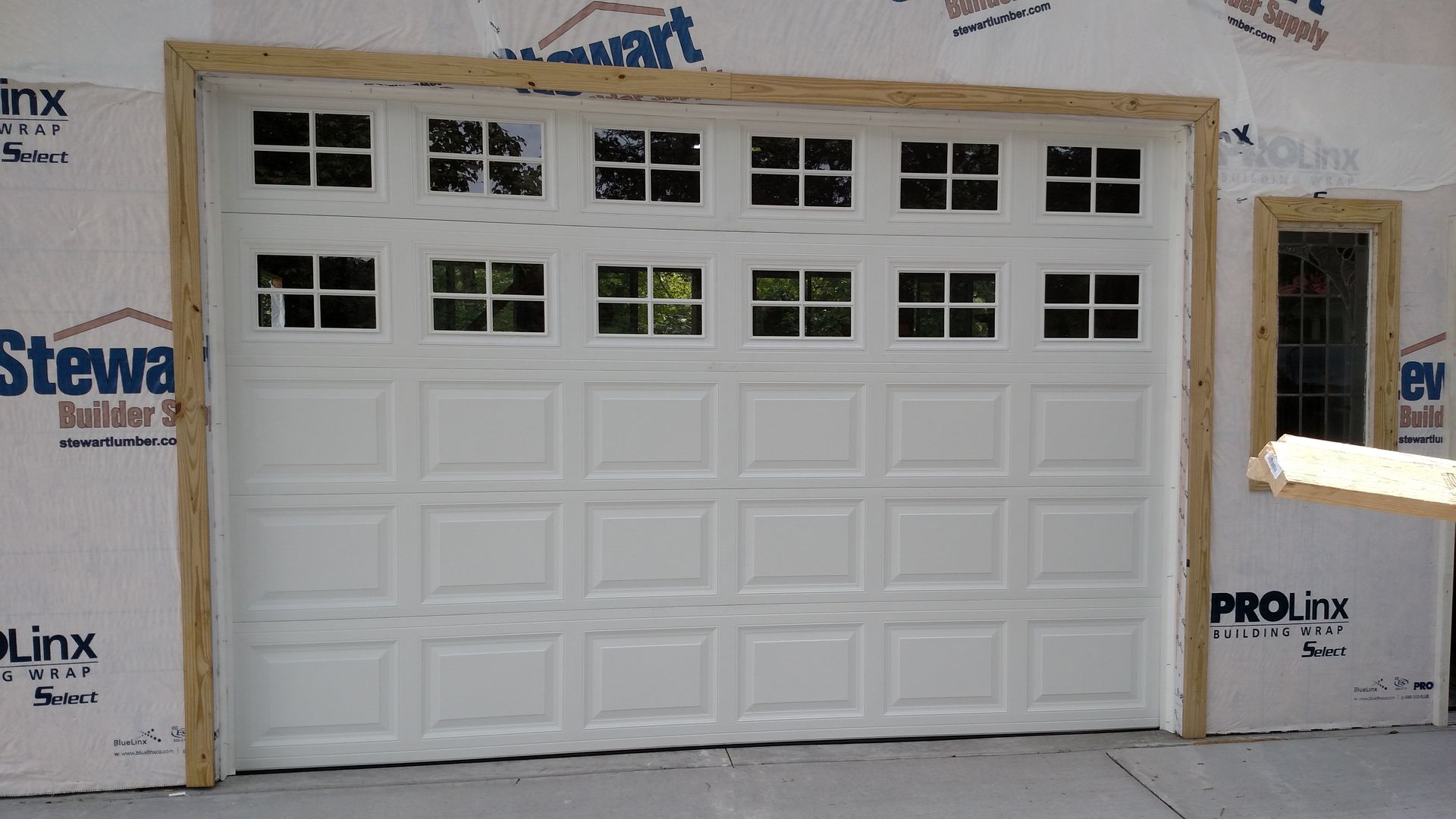 White garage door installed in a framed house opening with small windows along the top