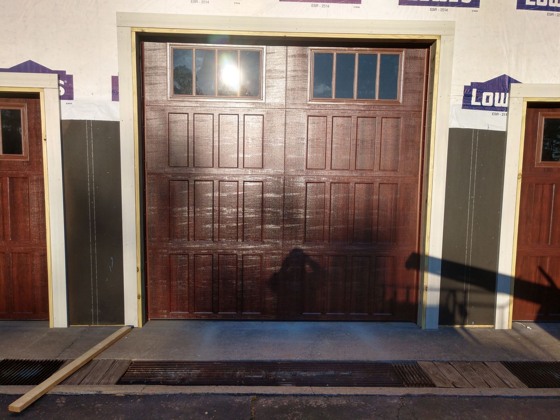 Closed brown garage-style doors on a building exterior with a sidewalk in front