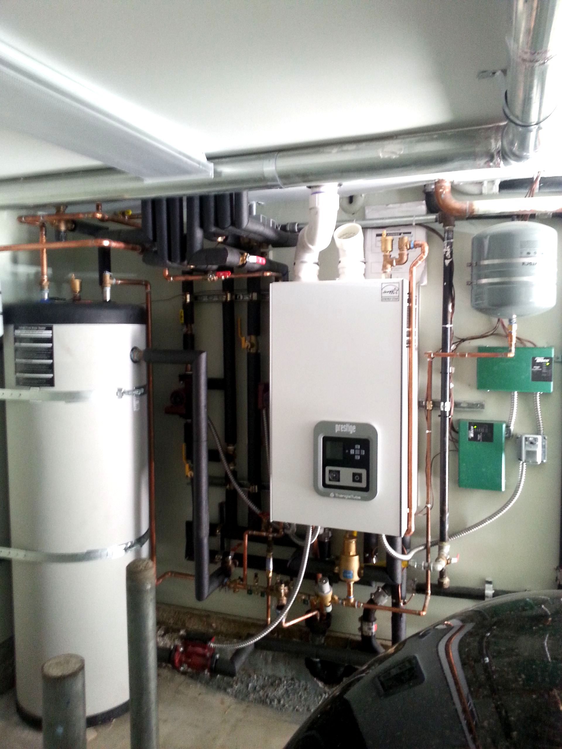 Heating system with boiler, water tank, and pipes in a basement setting.