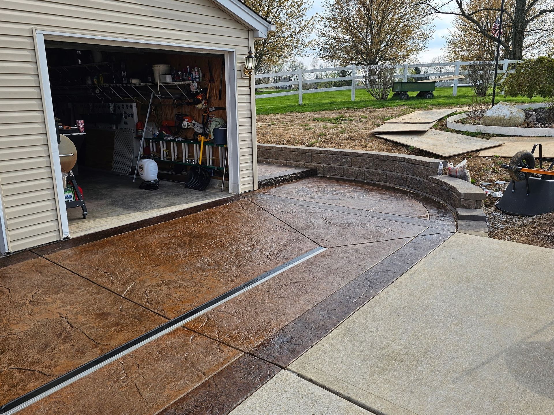 A concrete walkway leading to a garage with a fence in the background.