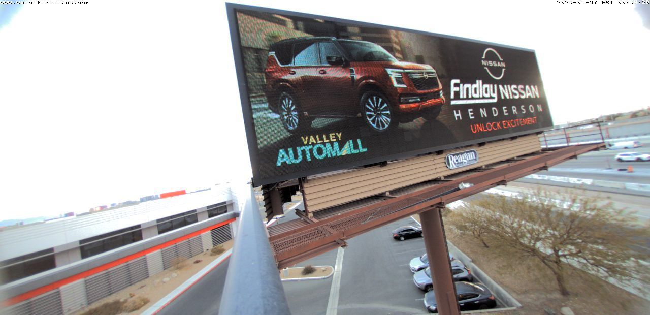 Roadside billboard advertising a red SUV near a snowy highway, tilted against a cloudy sky