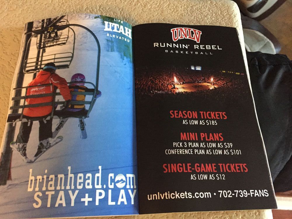 Open brochure with skiing scene and Utah logo on left, Runnin’ Rebels ticket ad on right.