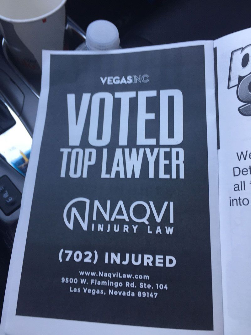 Black-and-white poster reading “Voted Top Lawyer” for Naqvi Injury Law, with contact details.