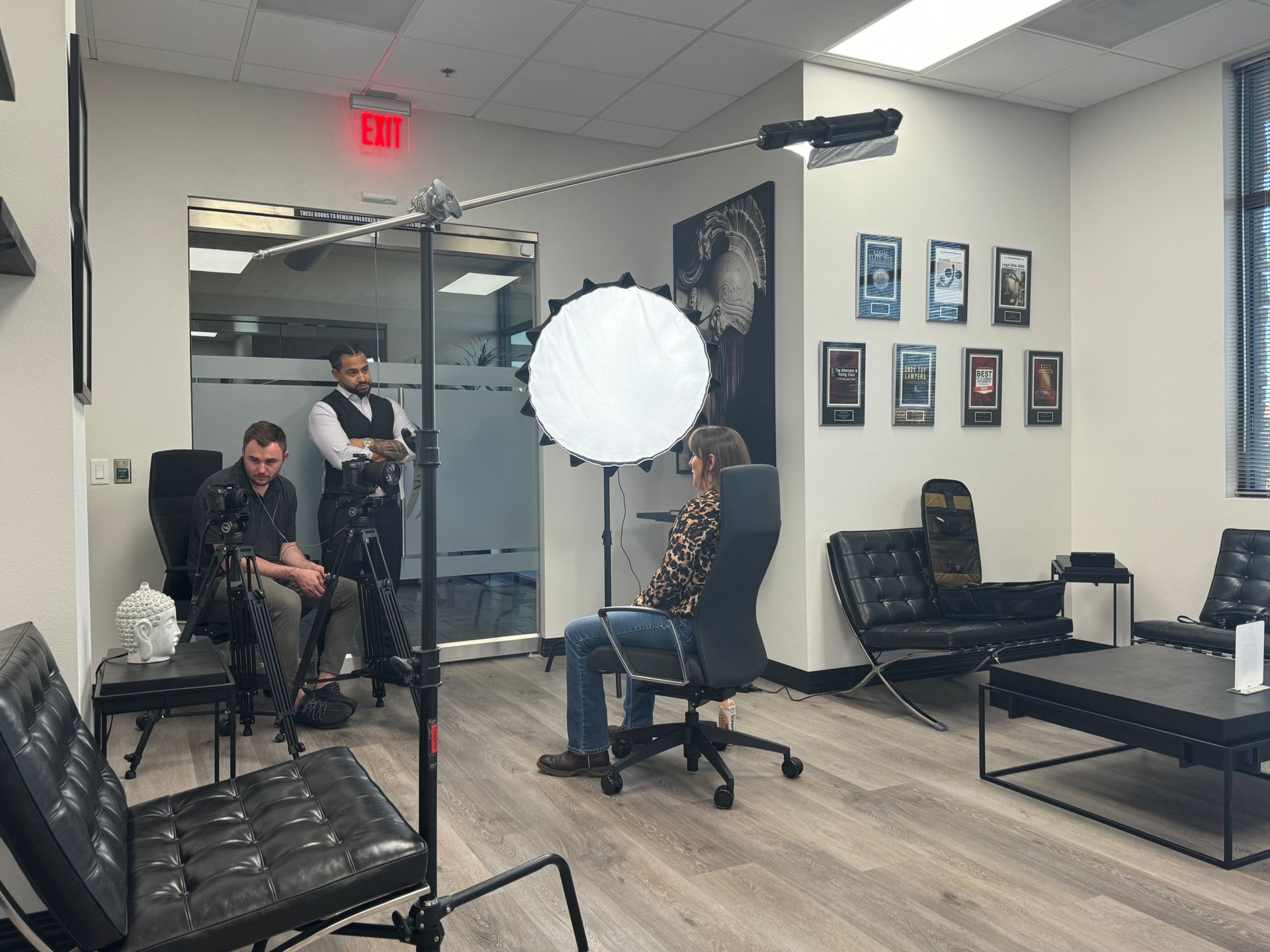 Photo studio with people seated and standing around a bright circular light setup.