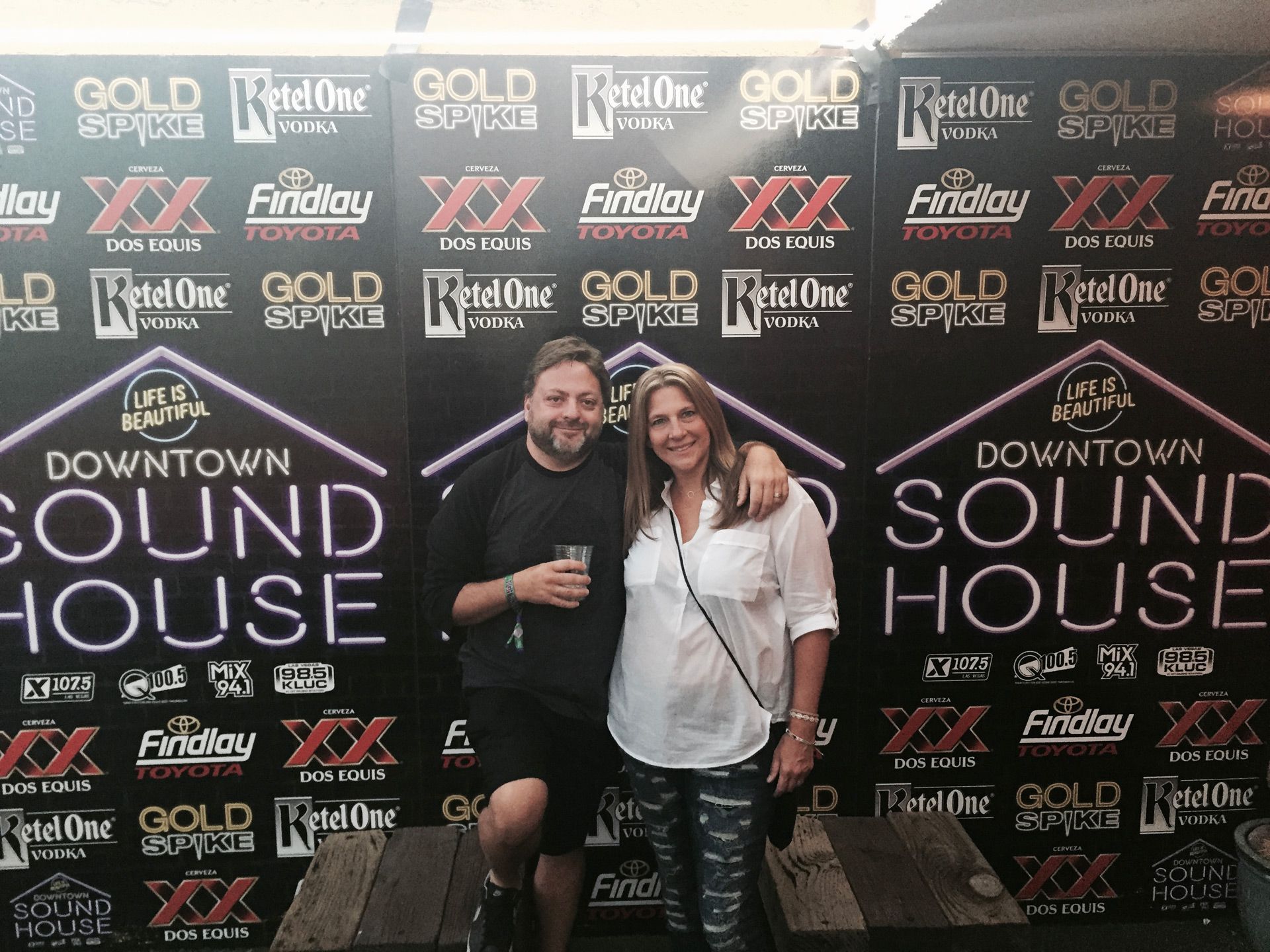 Two people posing and smiling at a Downtown Sound House event backdrop