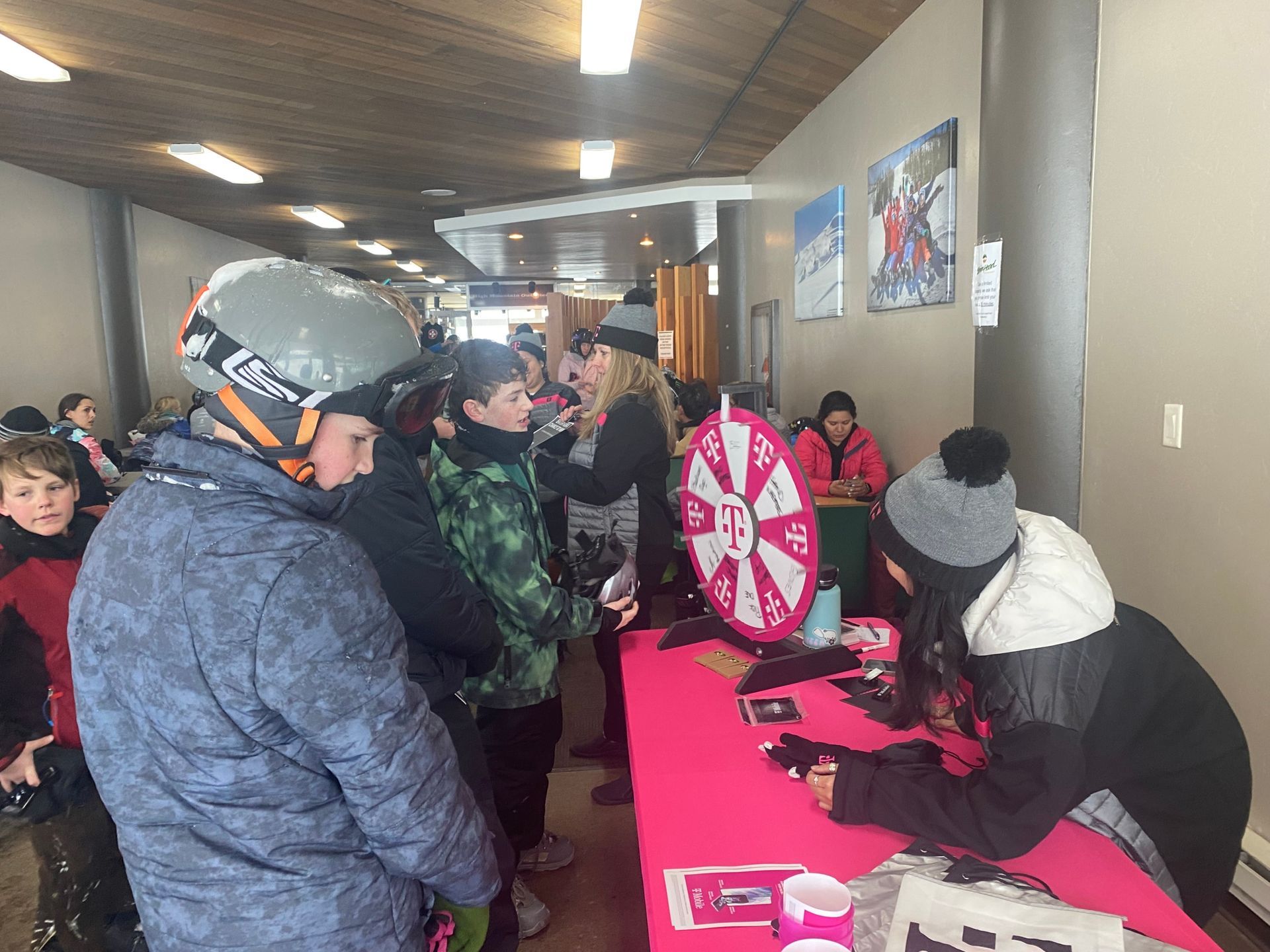 People gathered at a hallway table with a pink prize wheel and sign-in materials.