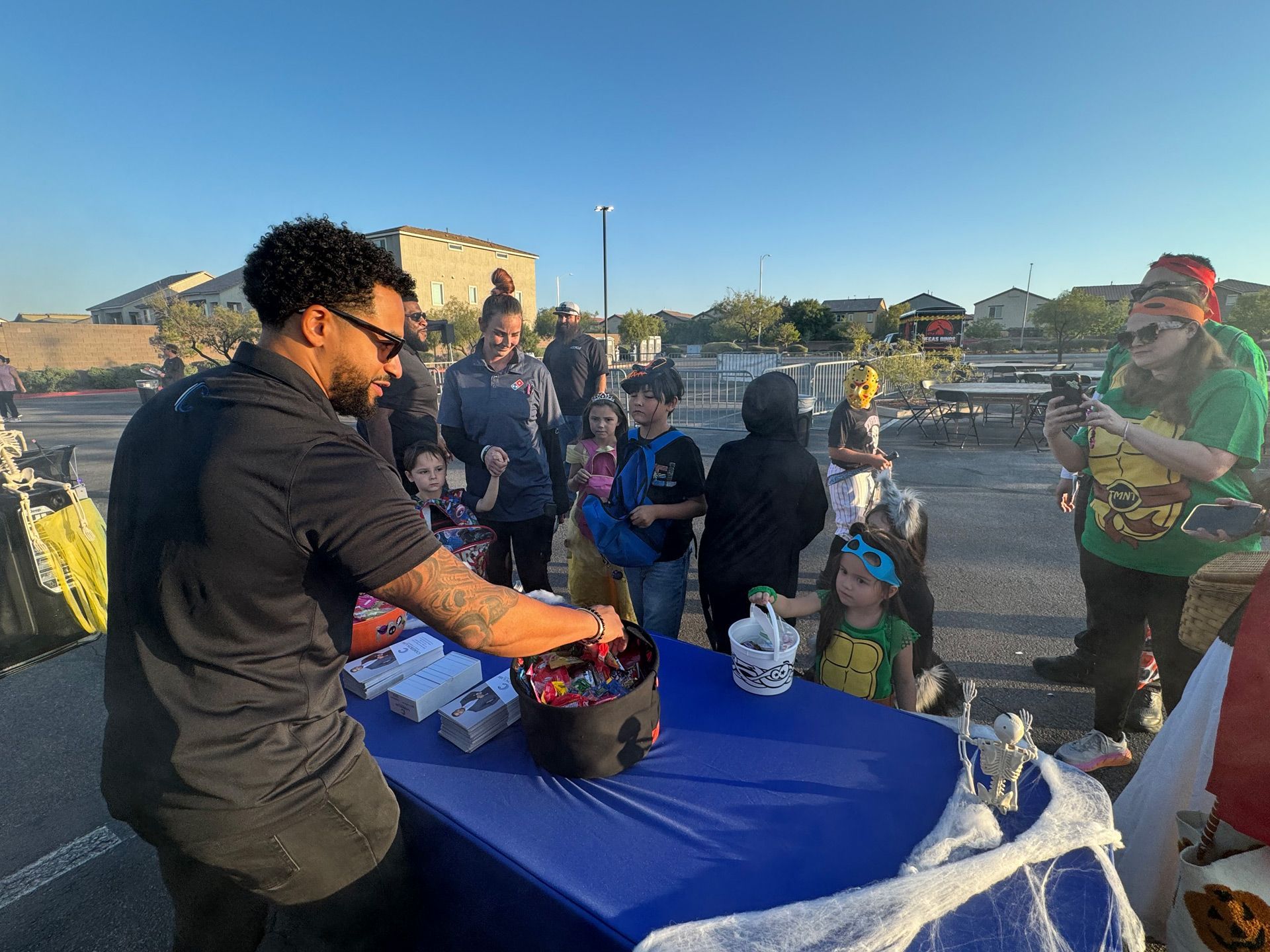 Man serving food from a table with a blue cloth at an outdoor community gathering