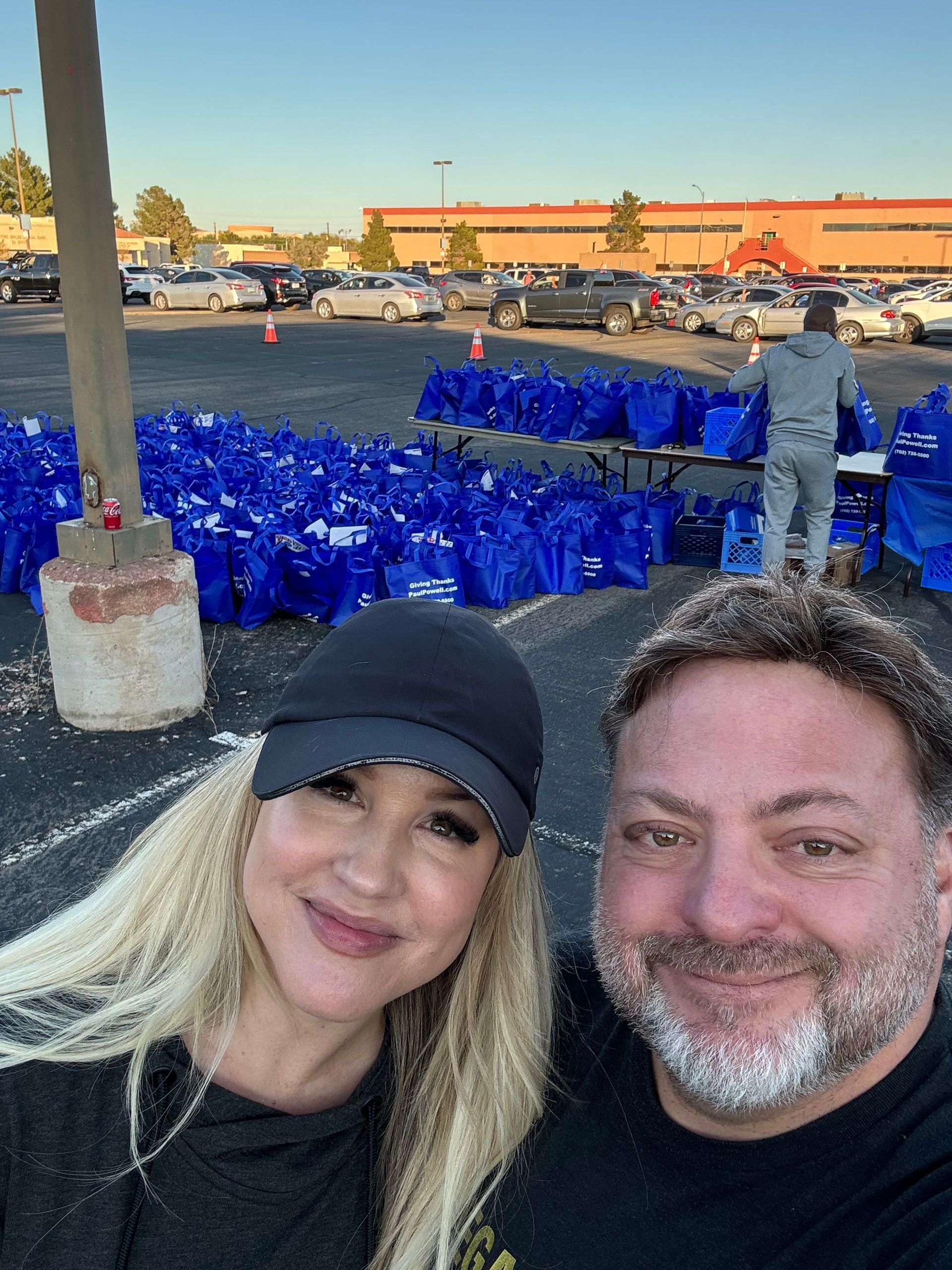Two people smiling at a large outdoor display of blue lights at dusk
