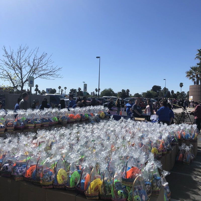 Rows of plastic-wrapped Easter baskets on tables at an outdoor market under a clear blue sky