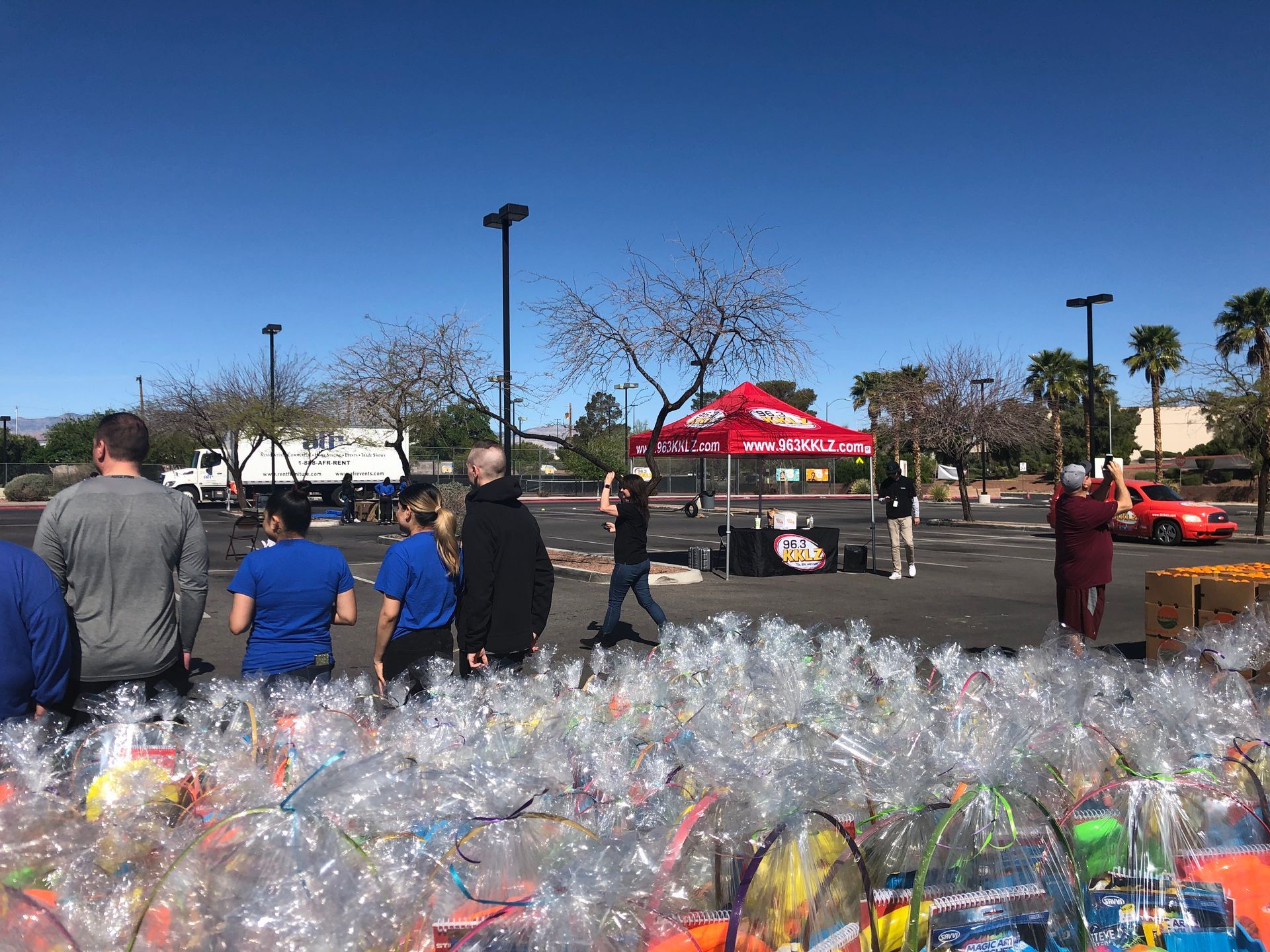People standing near a red tent beside a large pile of bagged donations outdoors