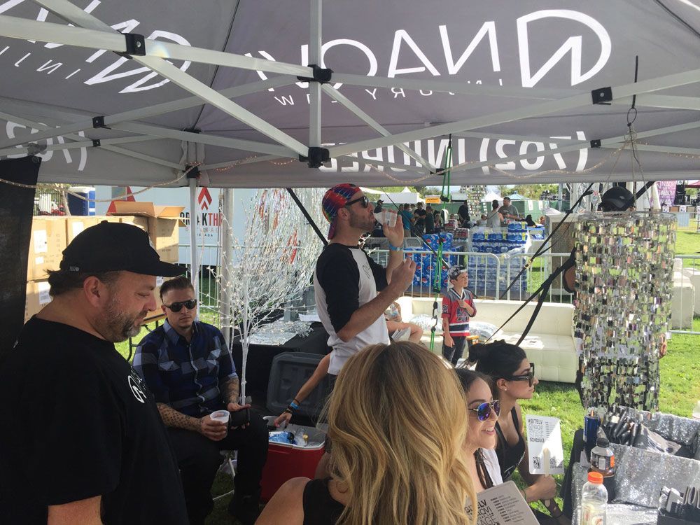 People under a tent at an outdoor event, with one person speaking into a microphone.