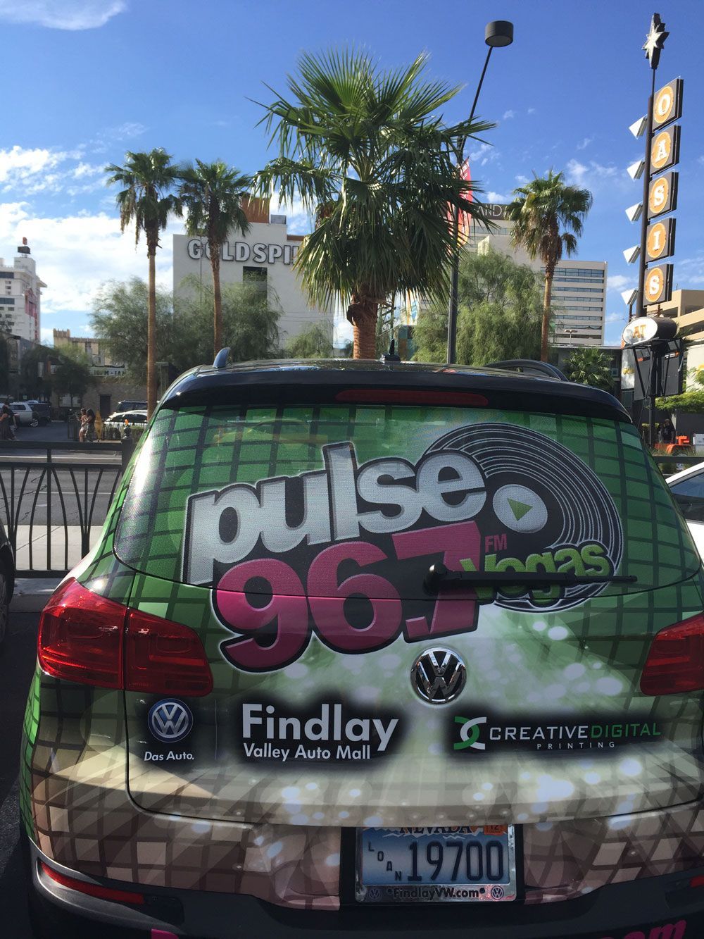 Purple Pulse 96.3 station SUV with vinyl wrap parked outdoors near palm trees and a church.