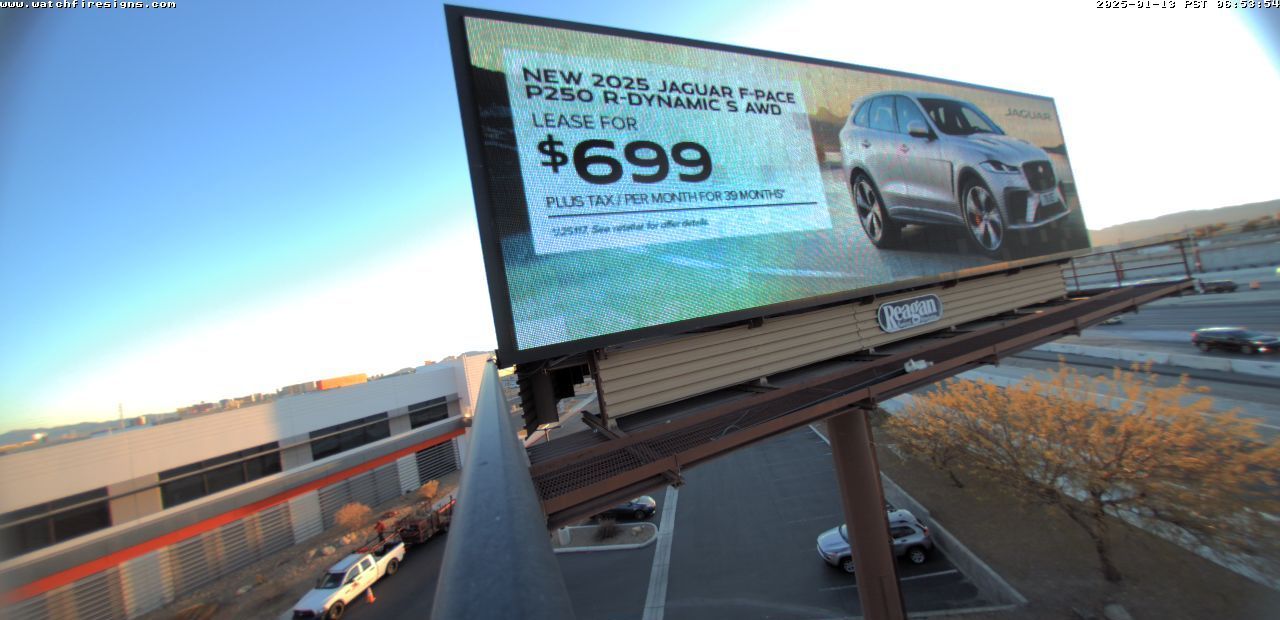 Billboard ad for a silver SUV on a roadside overpass at sunset, with a $699 price shown.