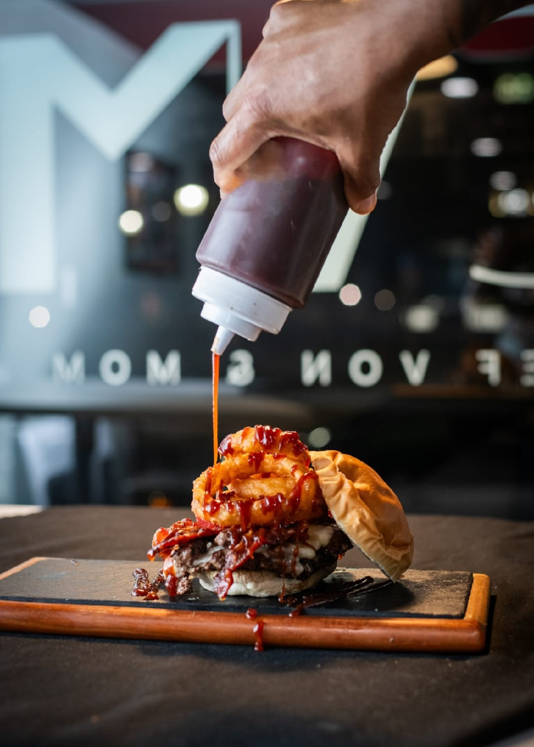 Rodeo burger with BBQ sauce being drizzled onto it