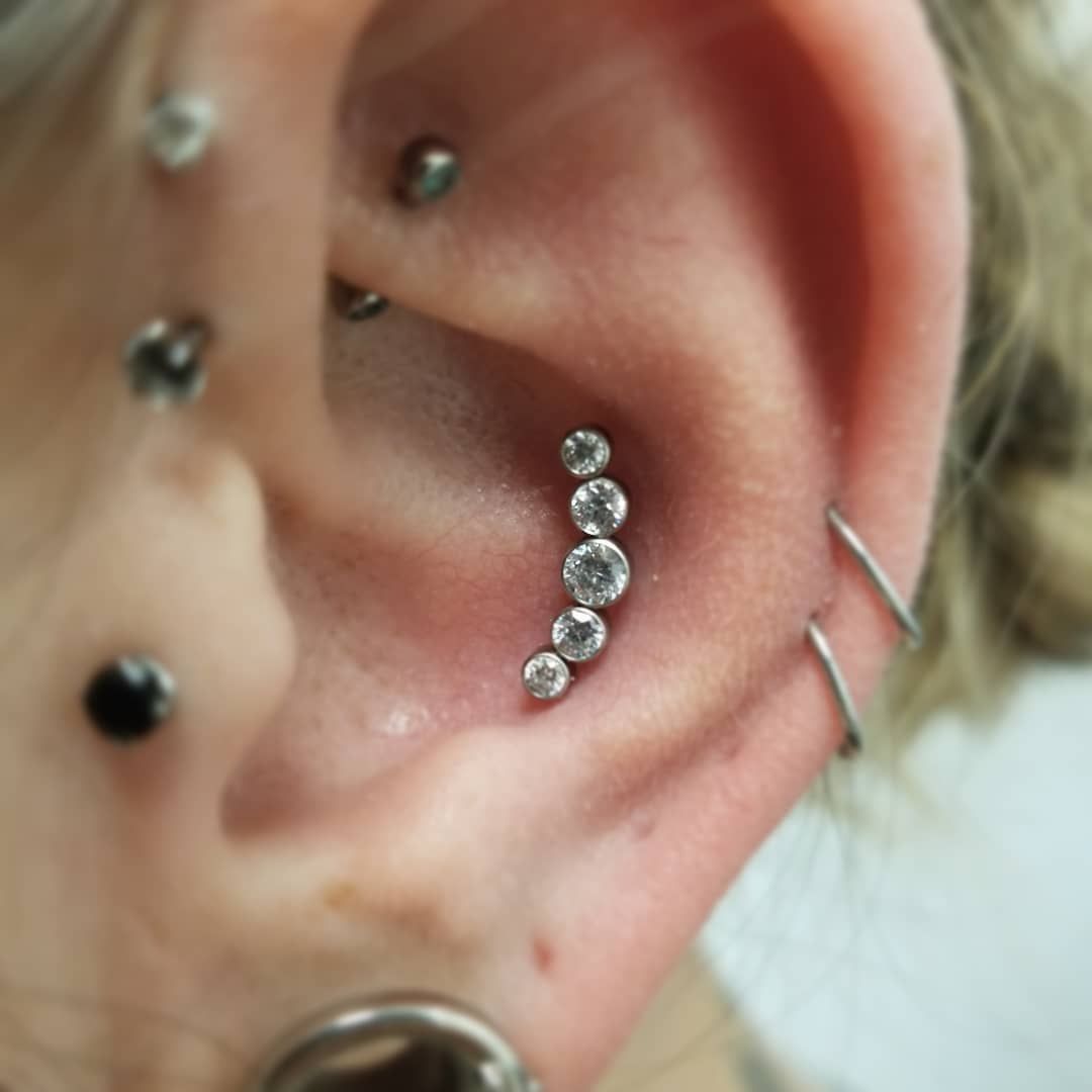 A close up of a woman 's ear with multiple piercings
