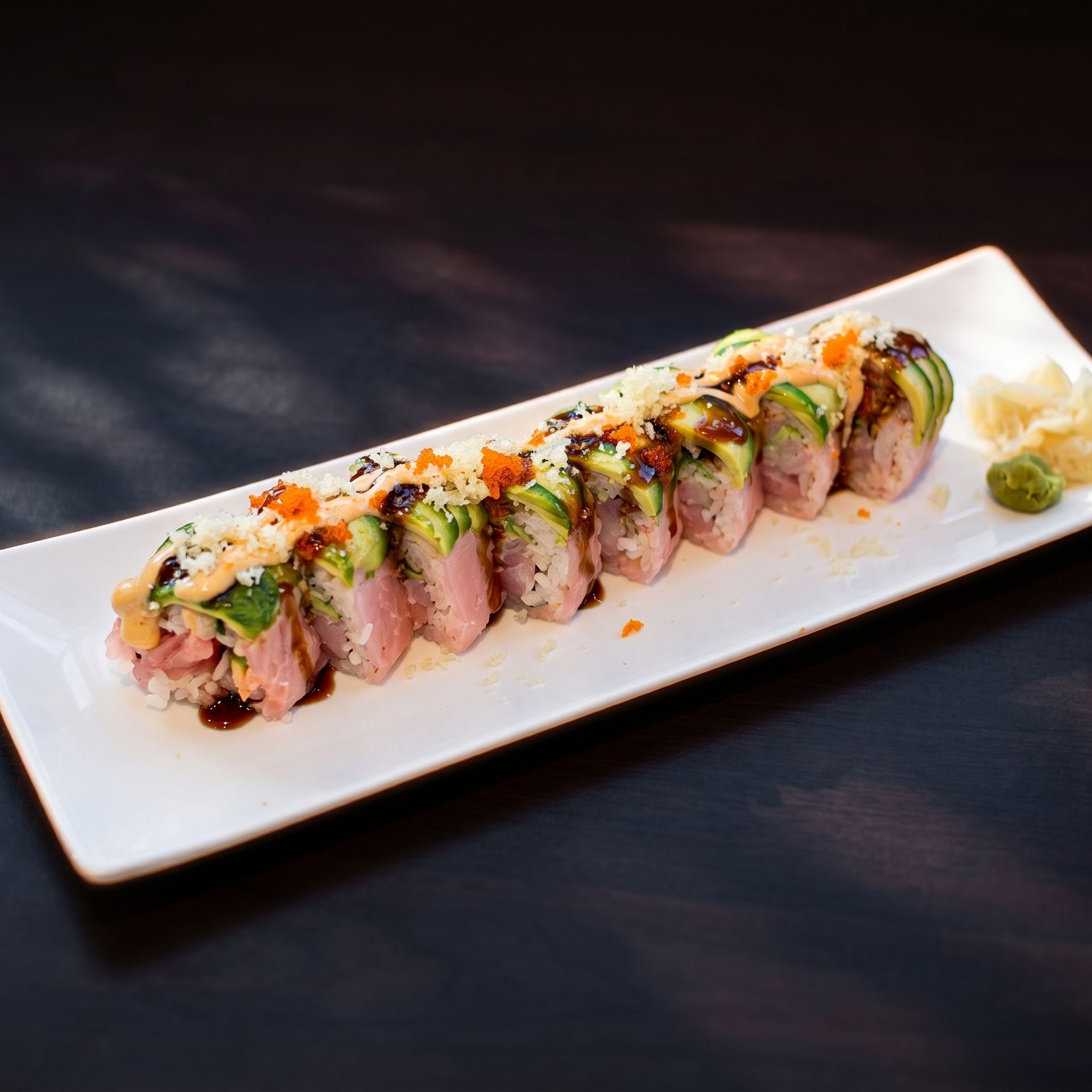 Sliced seared meat topped with herbs and sauce on a white rectangular plate