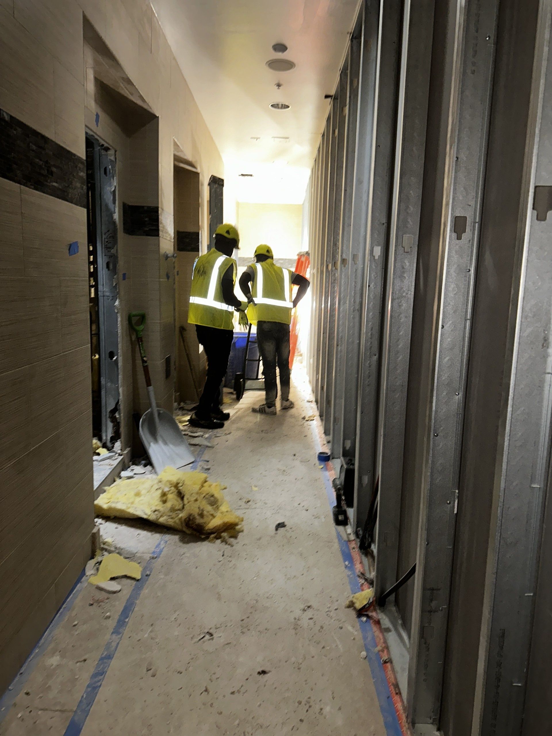 Worker in red hard hat demolishing a wall with a sledgehammer inside a renovation site
