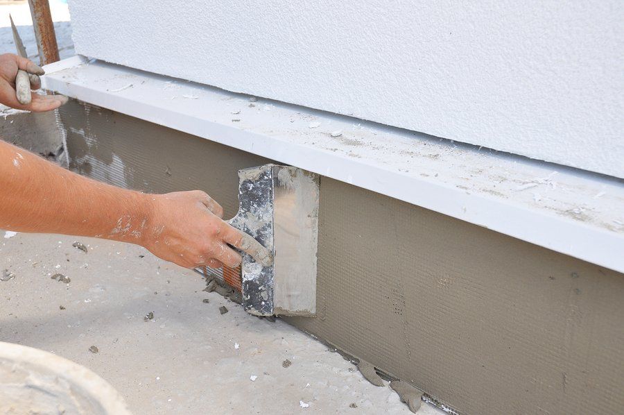 Worker applying filler for crack repair on the lower area of the house