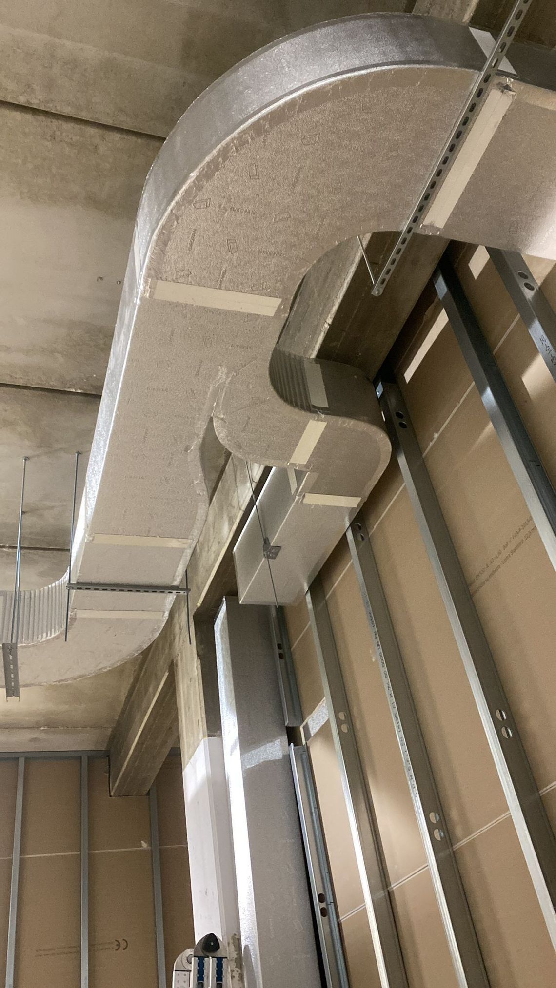 Condotti di climatizzazione metallici che corrono lungo un soffitto industriale con struttura a vista.