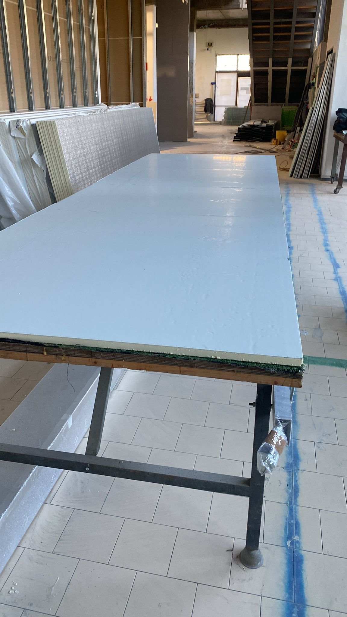 Un grande lenzuolo bianco su un tavolo da lavoro in una stanza non rifinita con struttura e isolamento a vista.