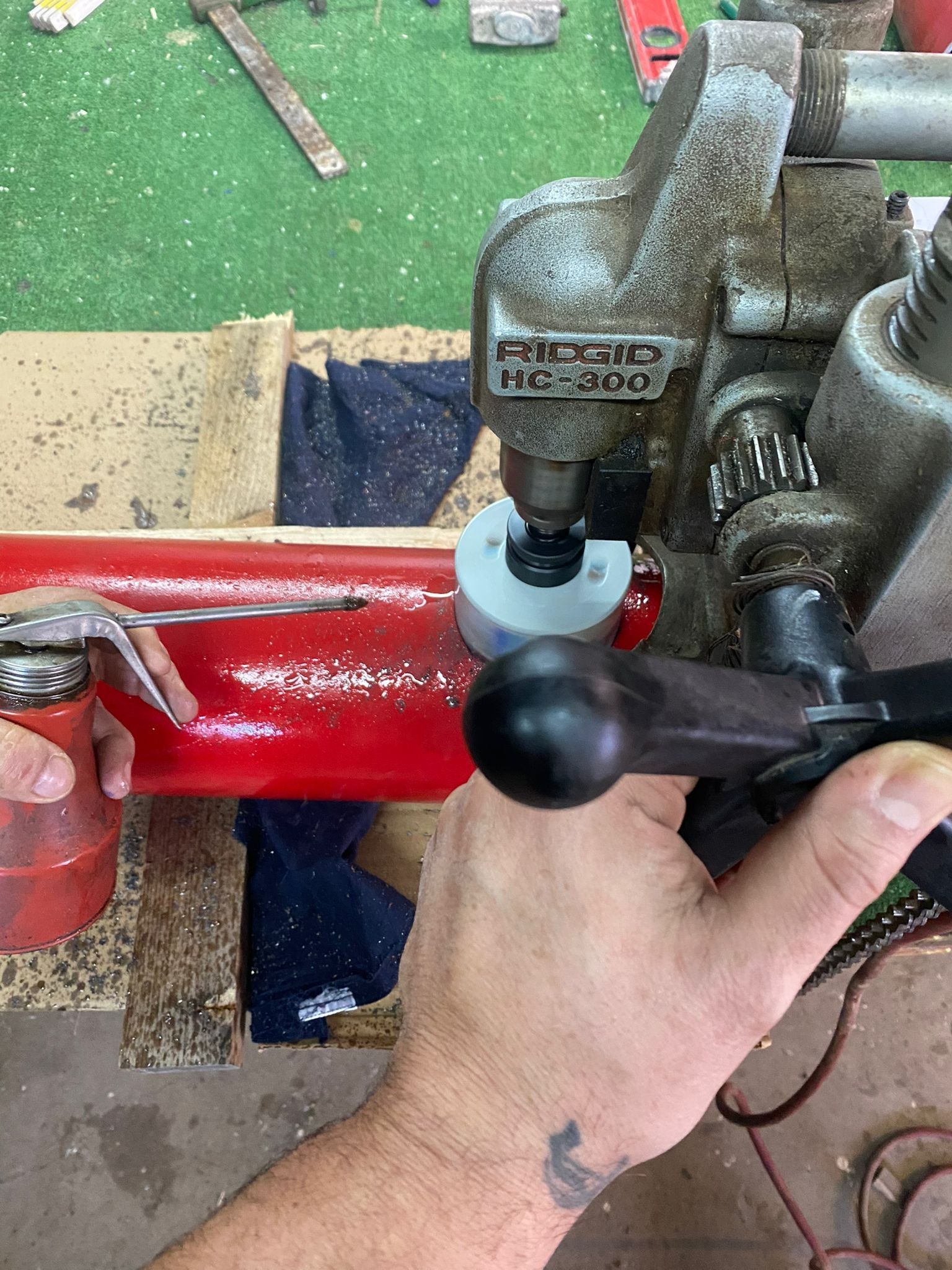 Una mano che ruota una maniglia nera su una morsa metallica rossa su un banco da lavoro