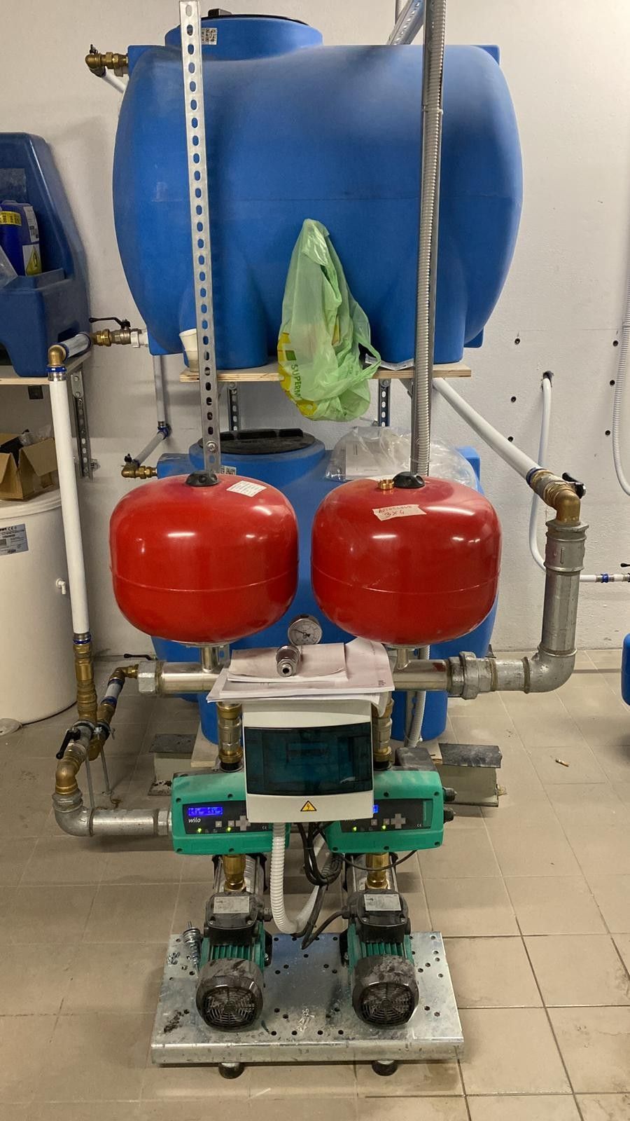 Macchinario industriale con serbatoio blu e serbatoi a pressione rossi su un telaio metallico in un'officina.