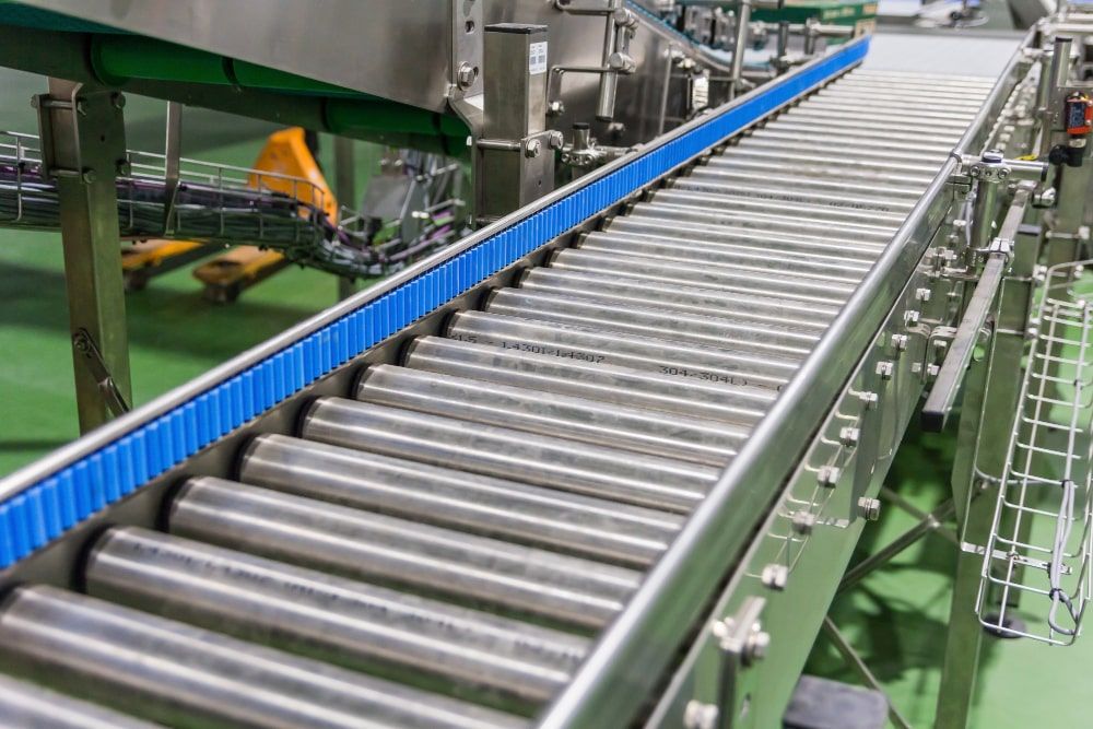 A stainless steel conveyor belt with a blue belt in a Florida factory.