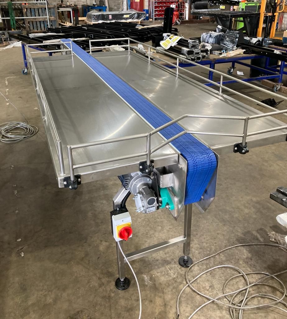 A conveyor belt is sitting on top of a stainless steel table in a factory.