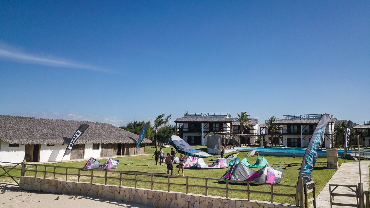 Uma casa branca com uma varanda de madeira é cercada por palmeiras
