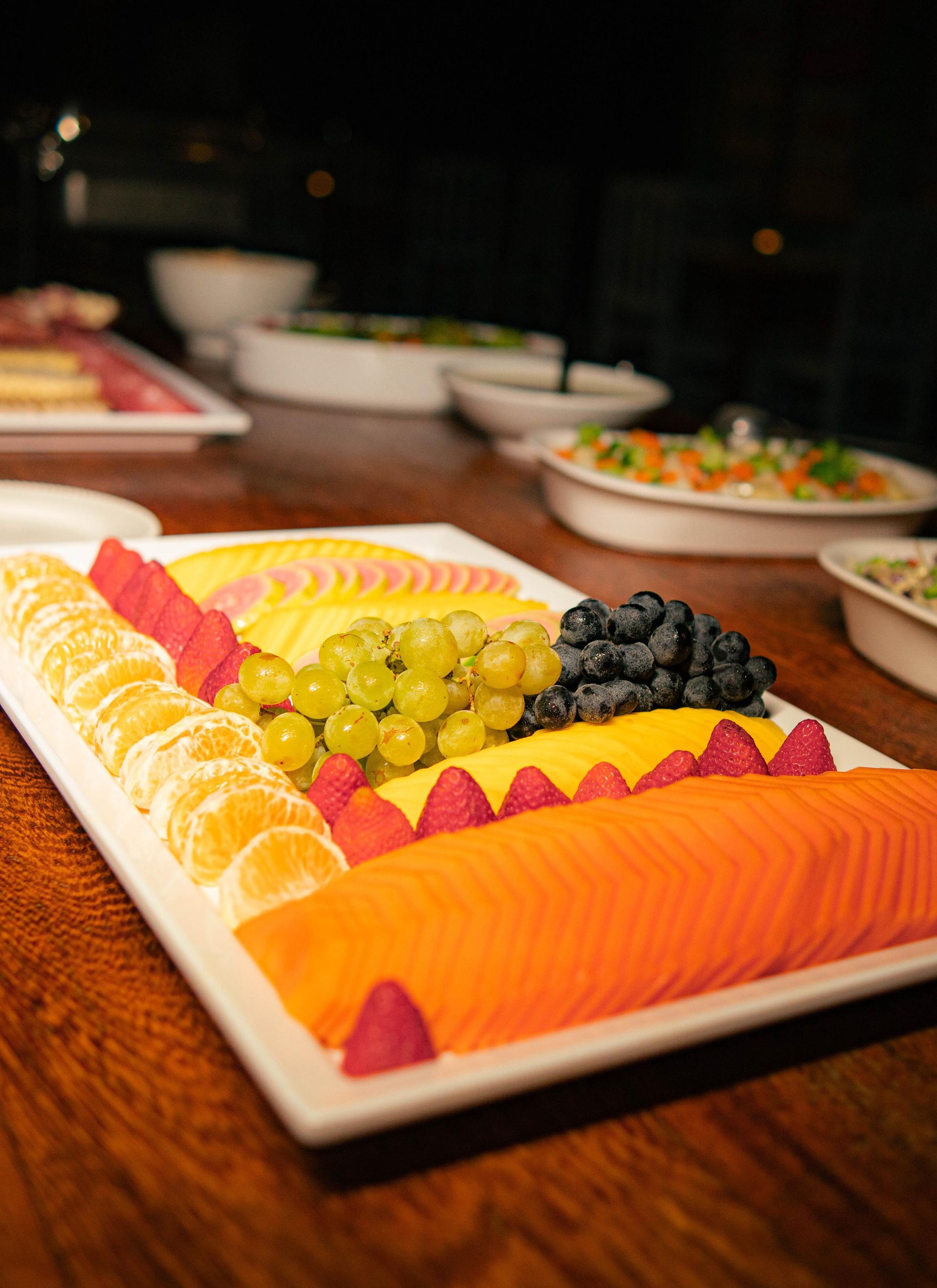 Uma bandeja de frutas está sobre uma mesa de madeira.