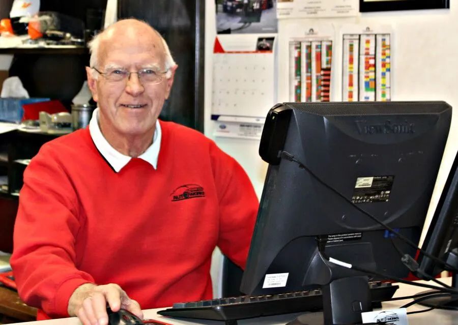 Man in a red sweater sitting at a desk with a computer in an office setting