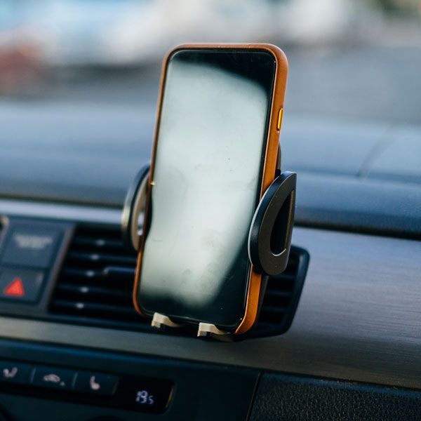 Smartphone in orange case mounted on a car dashboard phone holder