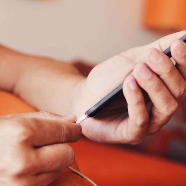 Hands holding a smartphone while connecting a charging cable against an orange background