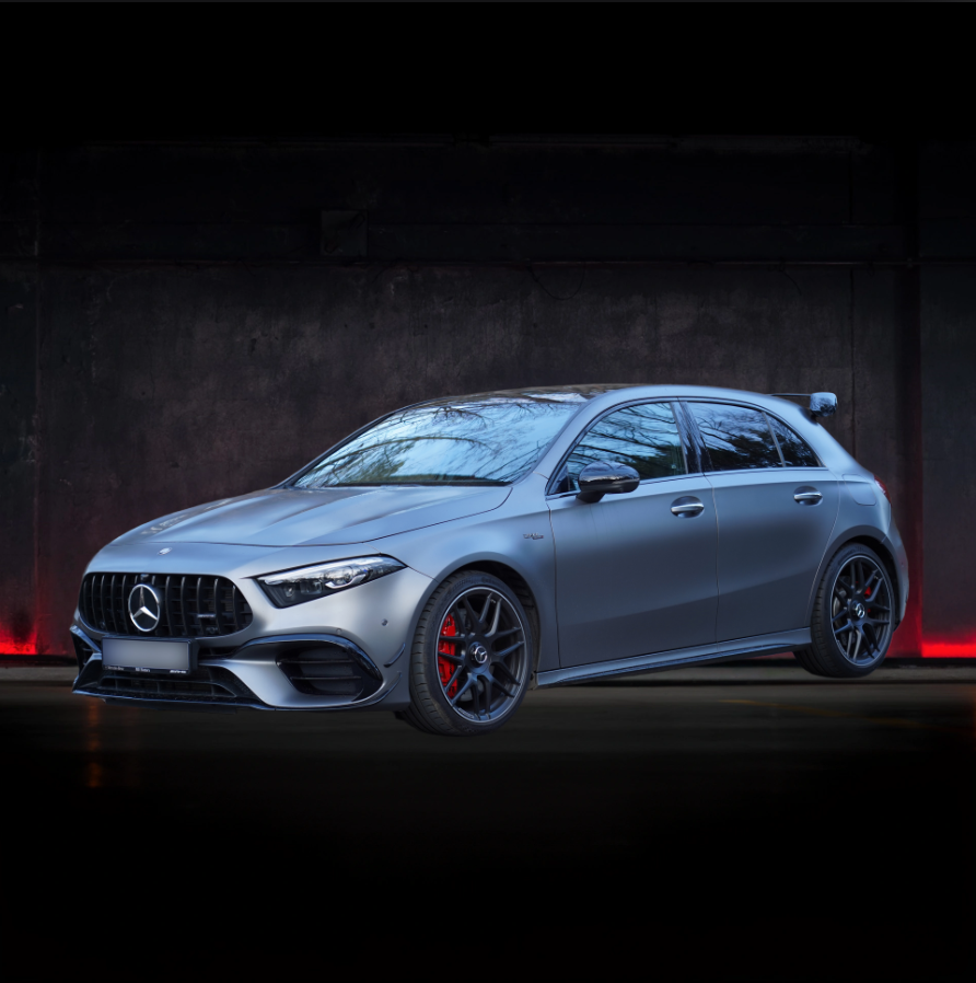 Una mercedes benz classe a berlina è parcheggiata davanti a un muro scuro.
