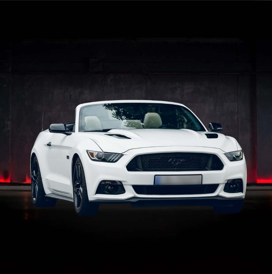 Una mustang bianca decappottabile è parcheggiata davanti a un muro scuro