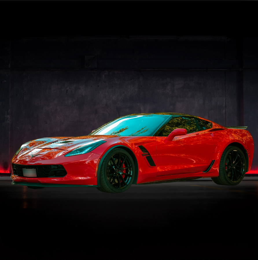 Un'auto sportiva rossa è parcheggiata davanti a un muro scuro.