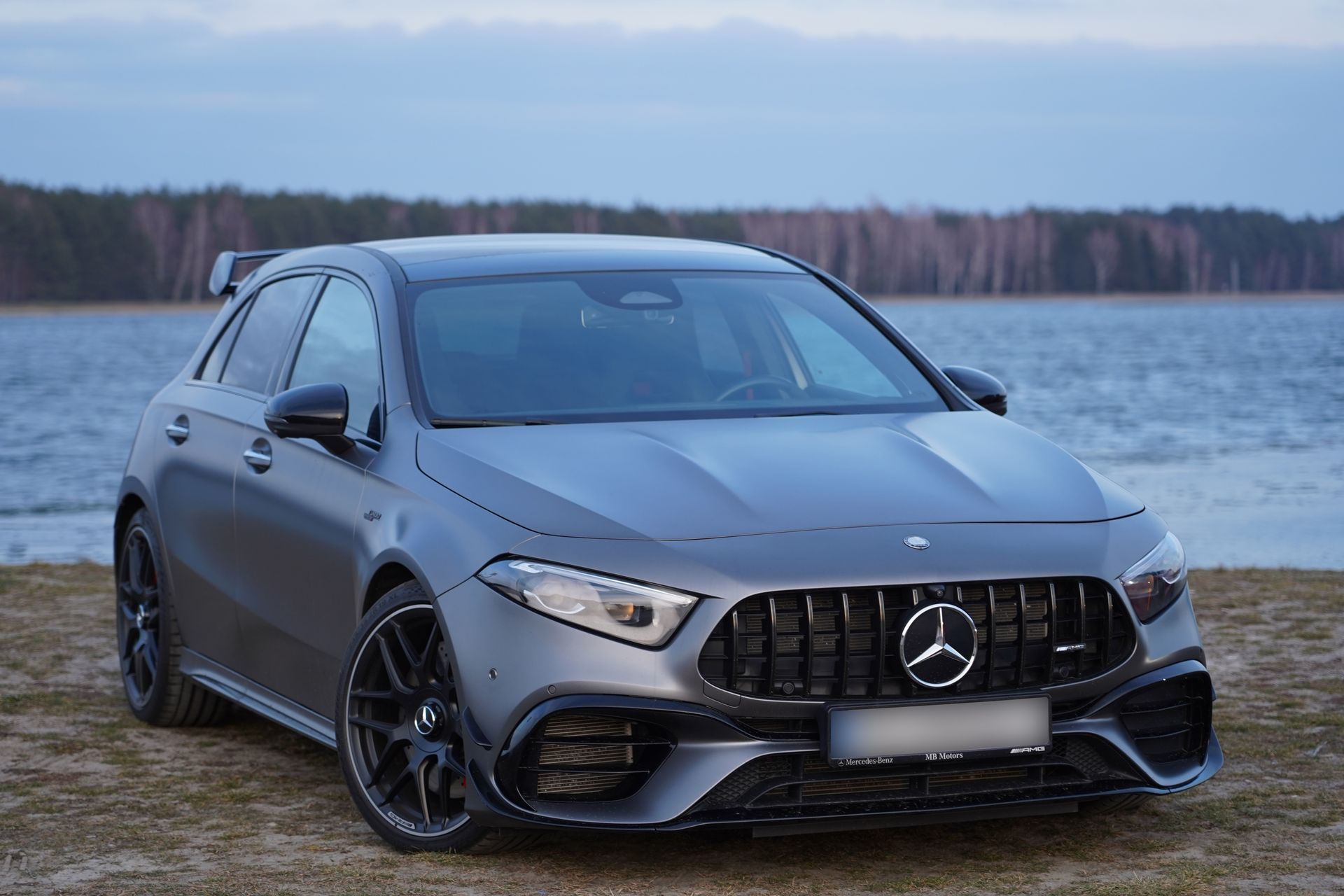 Una mercedes benz classe a è parcheggiata sulla spiaggia, vicino a uno specchio d'acqua.