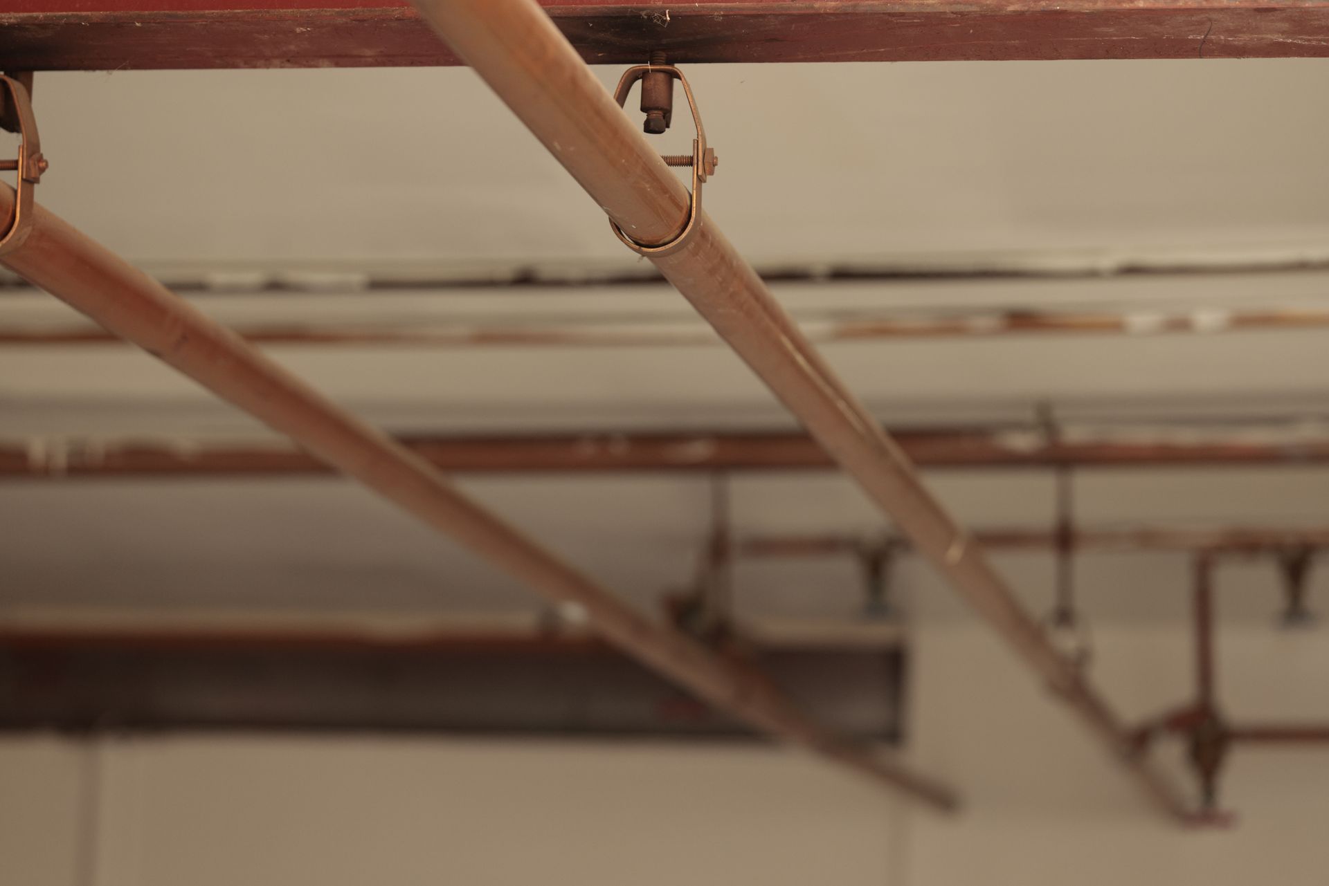Copper pipes and ceiling pipes running across an unfinished indoor ceiling