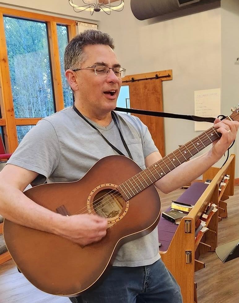 Priest playing acoustic guitar and singing