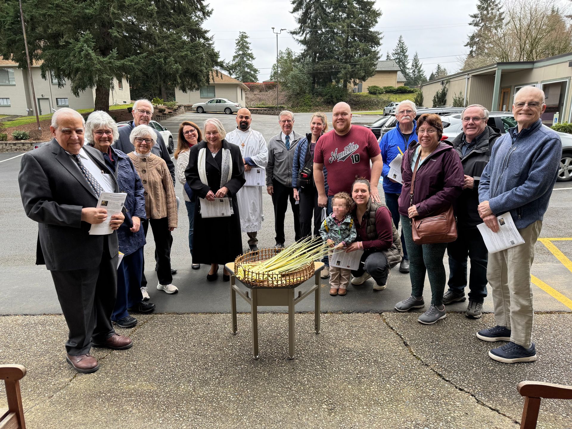 Parishioners gathered outdoors around a table with Palm Sunday palms