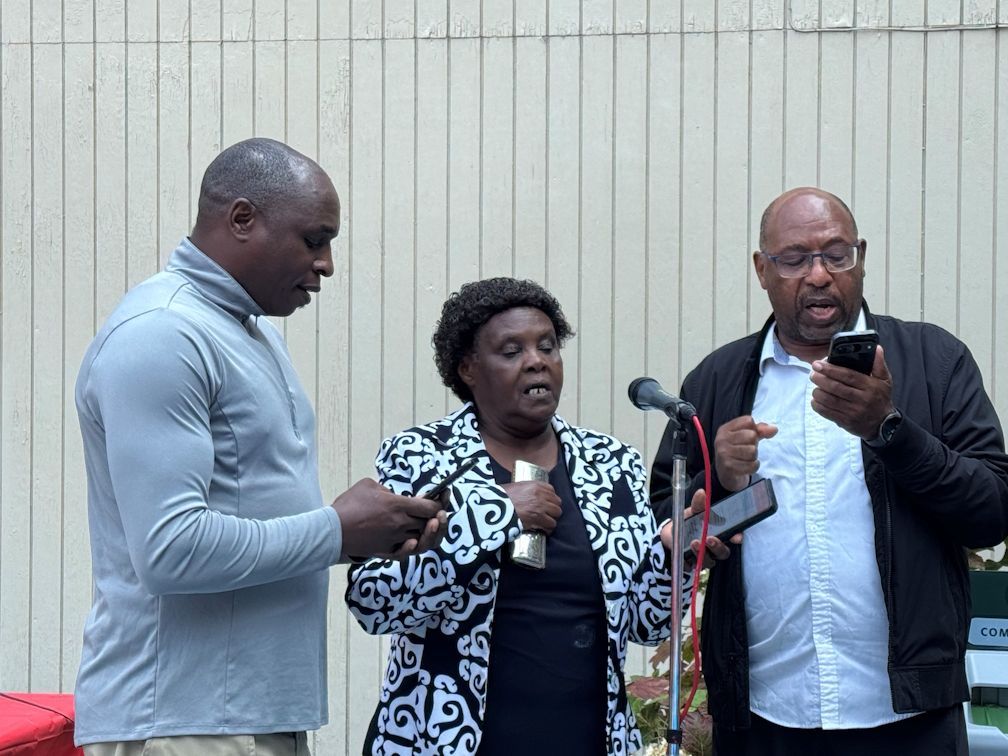 Three people singing at a microphone