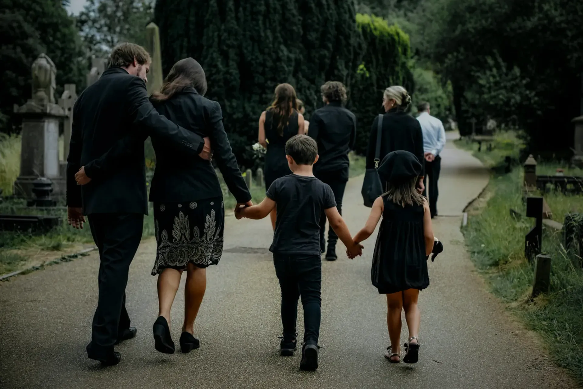 Group of people walking hand in hand along a tree-lined path in a park