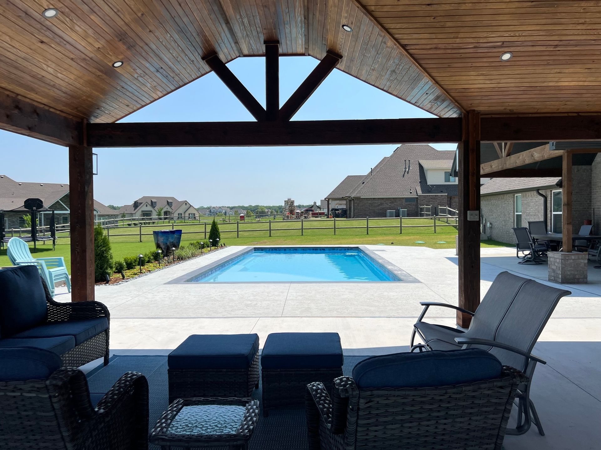 There is a large swimming pool in the backyard of a house.