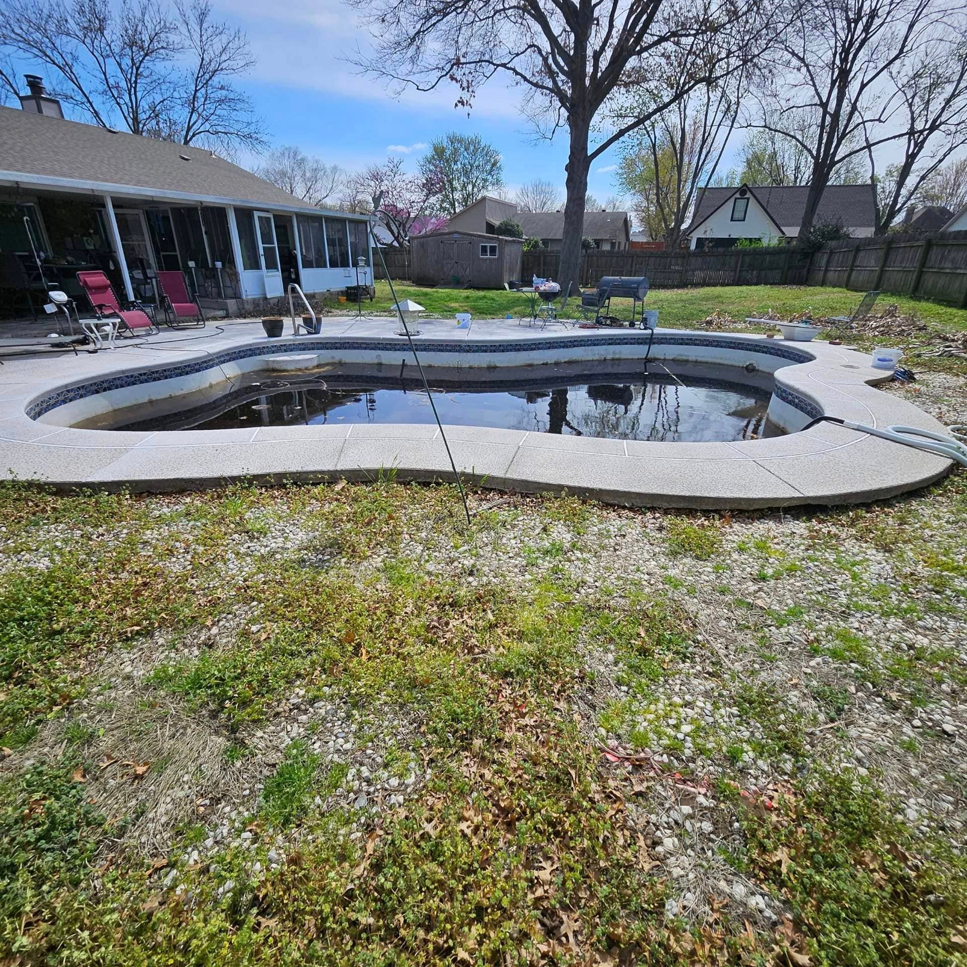A swimming pool is sitting in the grass in front of a house.