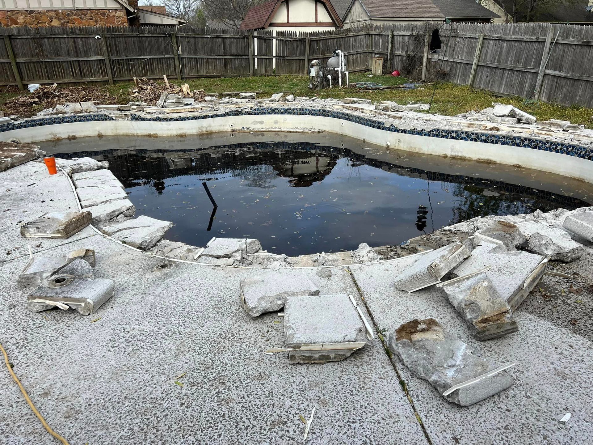 A swimming pool is being demolished in a backyard.